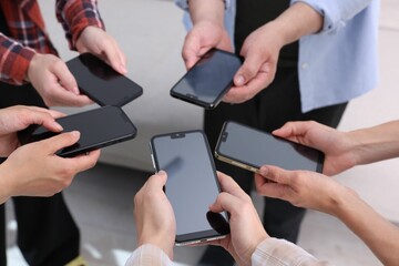 People holding smartphones with blank screens indoors, closeup