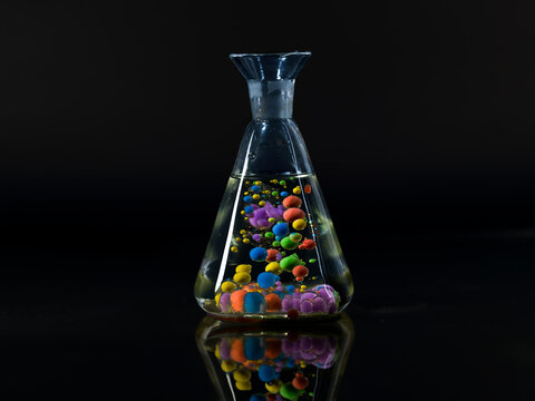 Spheres of paraffin oil and acrylic paint floating in a beaker of water