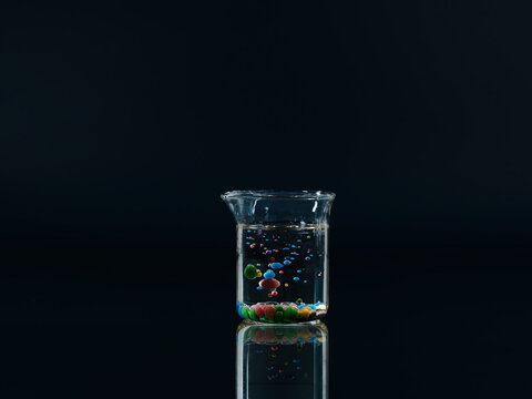 Spheres of paraffin oil and acrylic paint floating in a beaker of water
