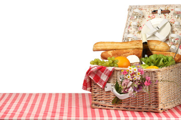 Picnic wicker basket with food, tableware, bottle of wine and flowers on table against white background. Space for text