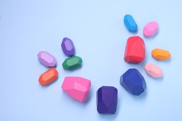 Many colorful balancing stones on light blue background, top view