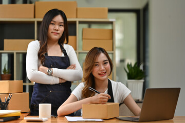 Small Business Teamwork, Two women confidently manage their small business, with one labeling a package and the other standing proudly beside, the SME concept
