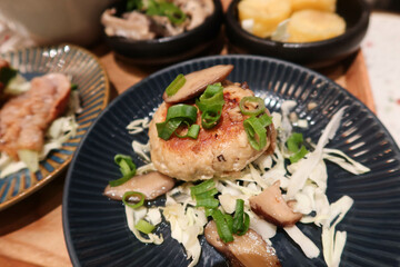 close up of Japanese style minced pork meat  patty cake with mushroom and spring onion on a blue plate