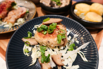 close up of Japanese style minced pork meat  patty cake with mushroom and spring onion on a blue plate