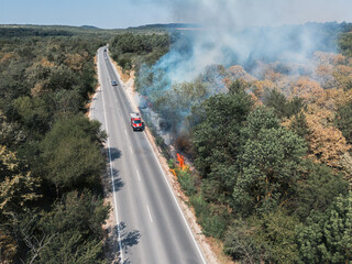 Obraz premium Abnormal temperature records led to a dry summer and fires in Europe. European road with burning bushes due and smoke to a thrown cigarette butt