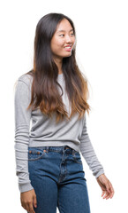 Young asian woman over isolated background looking away to side with smile on face, natural expression. Laughing confident.