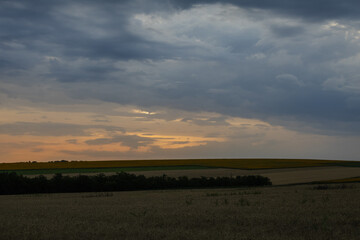 A landscape with a plain and a cloudy sky at sunset