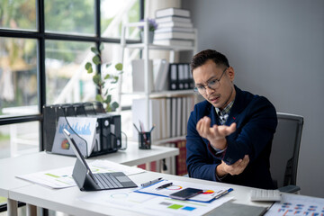 Fototapeta premium A man in a blue jacket is typing on a laptop computer at a desk