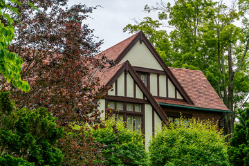 Fototapeta premium Tudor-Style House Surrounded by Lush Greenery and Trees in Newton, Massachusetts, USA