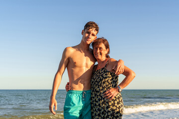 Hispanic woman in her 70s on the beach with her grandson, about 17 years old