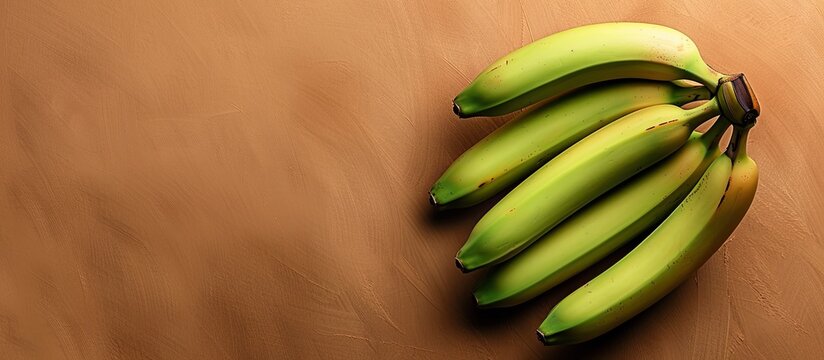 Green unripe bananas showcased on a warm toned brown backdrop with ample copy space image
