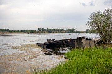 An old iron car in the green water of the river