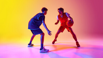 Two athletes practice basketball in vibrant lighting, displaying their agility and dedication in...