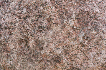 Large granite stone boulder texture background. Red granite old boulder with noise and grain in grunge style. Top view. Natural raw sheer cliff texture. Copy space.