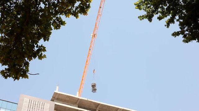 Crane moving construction materials against blue sky. Bottom up view