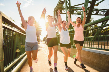 Obraz premium females in sportswear jogging together bright sunny park in summer