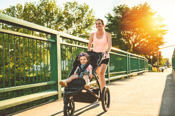 Young mother jogging with a baby buggy on sunset time
