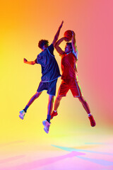 Powerful slam dunk. Dynamic basketball practice session with two athletes in neon light against...