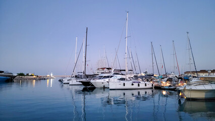 Fototapeta premium Some white yachts are parked in the harbor and are reflected in the blue water