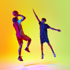 Basketball training. Two focused on victory athletes, during their dedication and intensity of their practice in neon light against gradient studio background. Concept of sport, competition, match. Ad