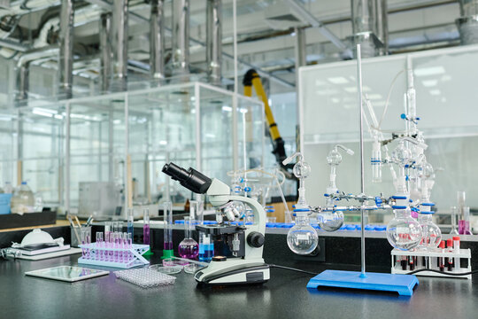 Variety of glassware, microscope, tablet, Petri dishes and other objects for carrying out scientific experiments on workplace of researcher