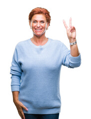 Atrractive senior caucasian redhead woman over isolated background smiling with happy face winking at the camera doing victory sign. Number two.