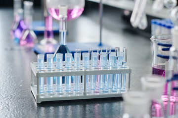 Group of flasks containing blue liquid substances standing in front of camera on workplace of chemist ready for new experiment