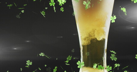 Image of st patrick's day green shamrock falling over beer glass © vectorfusionart