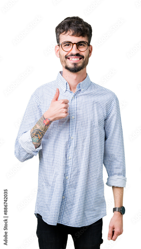 Poster Young handsome man wearing glasses over isolated background doing happy thumbs up gesture with hand. Approving expression looking at the camera with showing success.