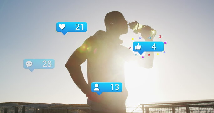 Image of social media icons and numbers over african american male athlete drinking water