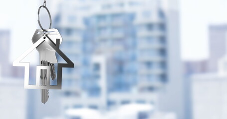 Image of hanging silver house keys against blurred view of tall buildings with copy space