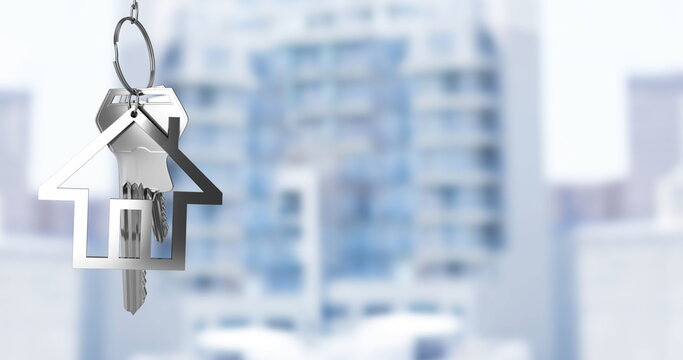 Image of hanging silver house keys against blurred view of tall buildings with copy space