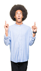 Young african american man with afro hair amazed and surprised looking up and pointing with fingers and raised arms.