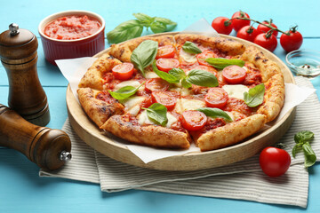 Delicious Margherita pizza and ingredients on light blue wooden table
