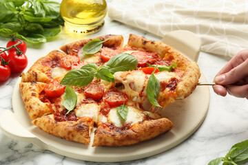 Woman taking piece of delicious Margherita pizza at white marble table, closeup