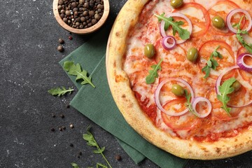 Delicious vegetarian pizza with arugula and peppercorns on black table, top view