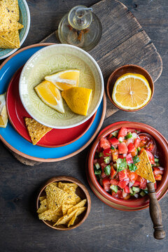 Overhead view of a bowl of Traditional Mexican Pico de Gallo salsa with tortilla chips and fresh lemon