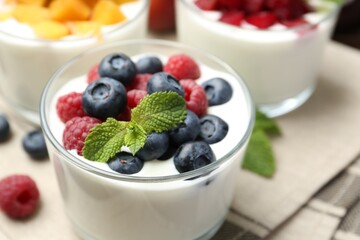 Tasty yogurt with fresh berries, fruits and mint in glasses on table, closeup
