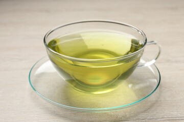 Refreshing green tea in cup on wooden table, closeup