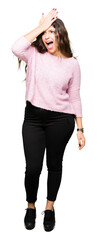 Fototapeta premium Young beautiful woman wearing pink sweater surprised with hand on head for mistake, remember error. Forgot, bad memory concept.
