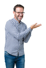 Handsome middle age elegant senior man wearing glasses over isolated background Pointing to the side with hand and open palm, presenting ad smiling happy and confident