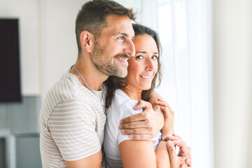 Fototapeta premium mid adult couple standing near of a window. Happy and romantic mature man embracing