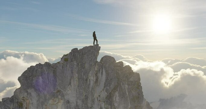 Adventurous Man Hiker standing on top of rocky peak with clouds around. Adventure Composite. 3d Rendering rocks. Aerial Image of landscape from BC, Canada. Sunny Sky. 3D Illustration