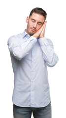 Handsome young businessman sleeping tired dreaming and posing with hands together while smiling with closed eyes.