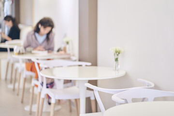 Abstract blurred coffee shop with a woman at a table in a supermarket on a light blurred background cafe with space to copy. High quality photo