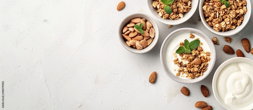 Poster top view of yogurt, granola, and almonds in bowls on a white surface with copy space image for an or