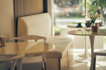 Selected focus: an empty glass table against the background of a coffee shop or restaurant window with a bokeh effect. White leather sofa for relaxing. High quality photo