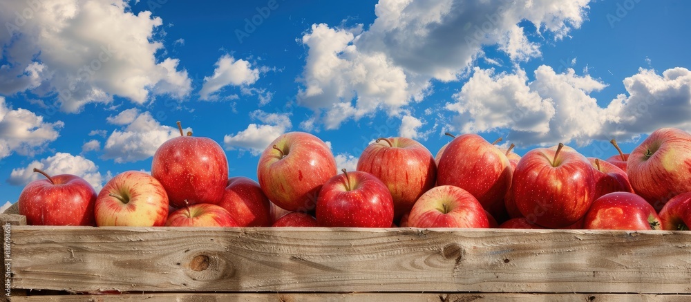 Aufkleber braeburn apples arranged in a wooden crate against a scenic blue sky with clouds, creating a vibrant