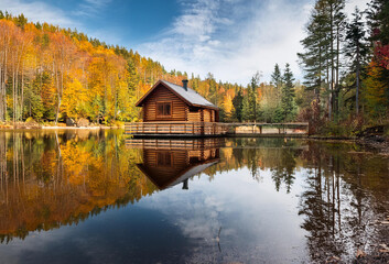 Tranquil reflections: A cozy log cabin nestles by the serene lakeside, embraced by the whispering woods