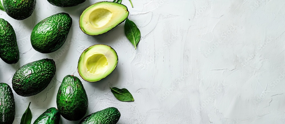 Poster Whole and sliced ripe avocados displayed from the top view on a white backdrop with ample copy space image.